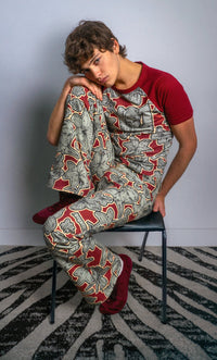 Person wearing a red and gray patterned outfit sitting on a chair against a plain background